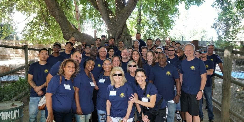 A group of people posing in front of a tree near Supreme Boats.