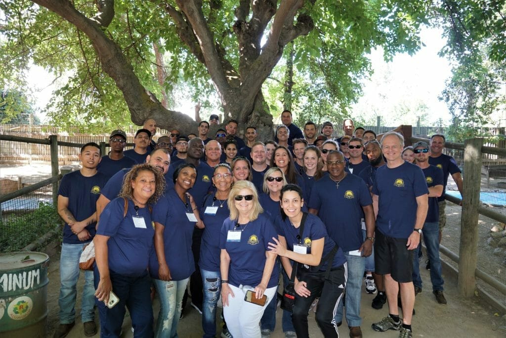 A group of people posing in front of a tree near Supreme Boats.