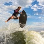 A man is surfing on a Supreme surfboard.