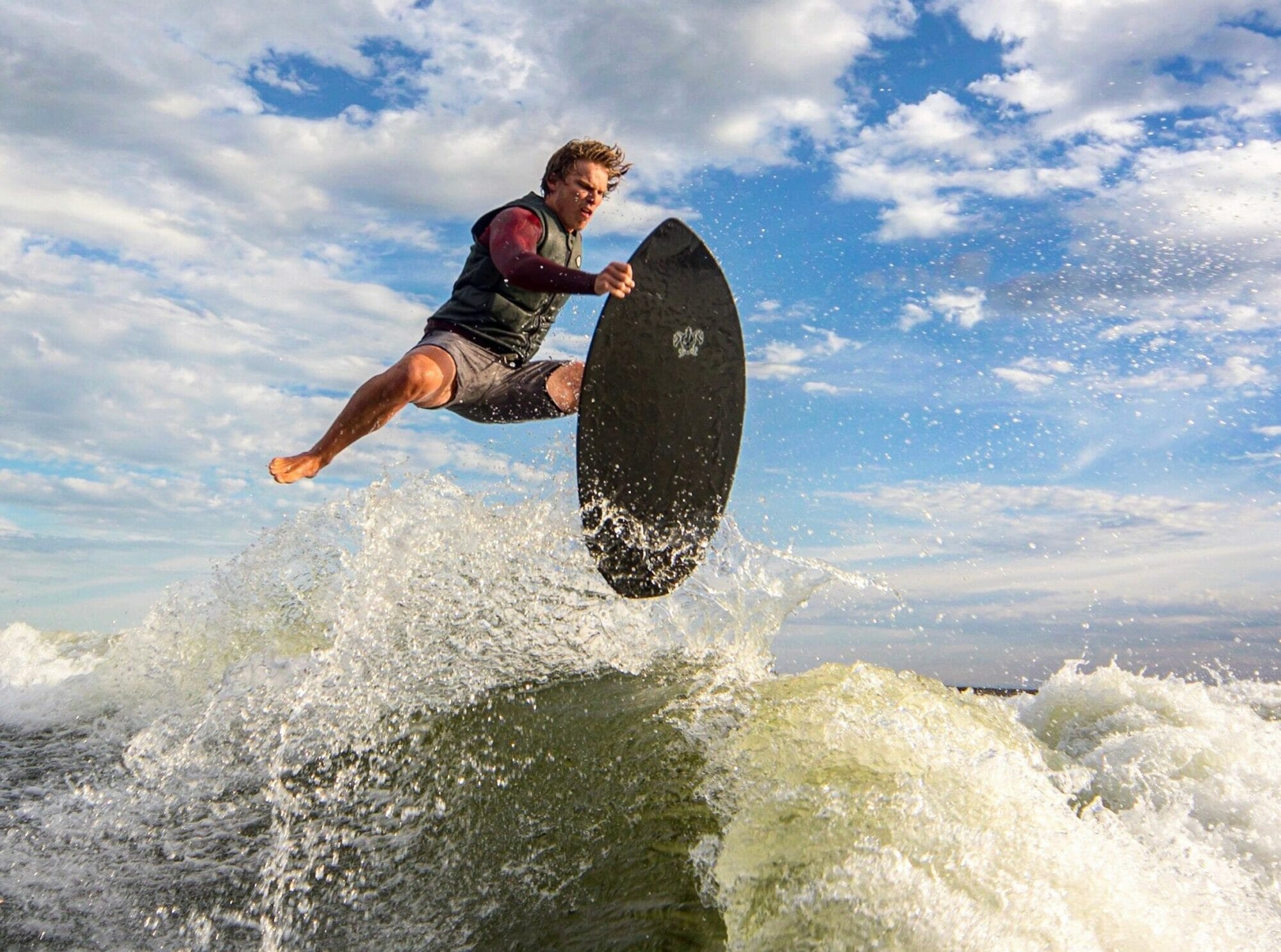 A man is surfing on a Supreme surfboard.