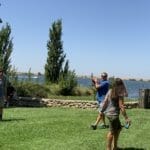 A group of people playing frisbee near a lake.