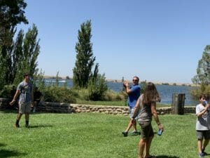 A group of people playing frisbee near a lake.