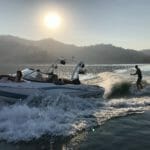 A man is riding a Supreme speed boat in the water.