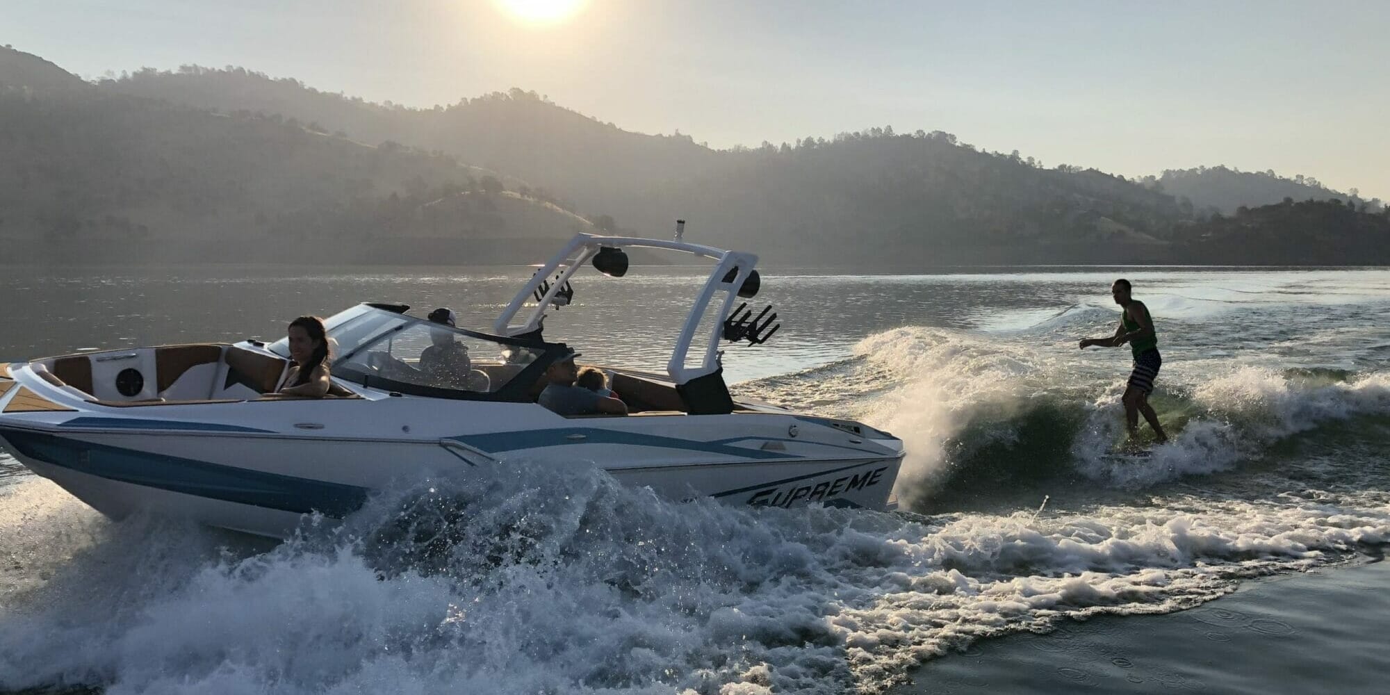 A man is riding a Supreme speed boat in the water.