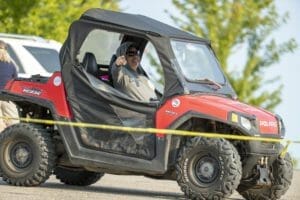 A man is driving a Supreme UTV in a parking lot.