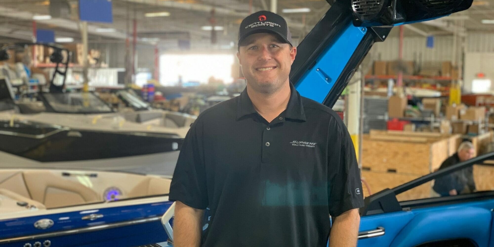 A man standing next to a Supreme boat in a warehouse.