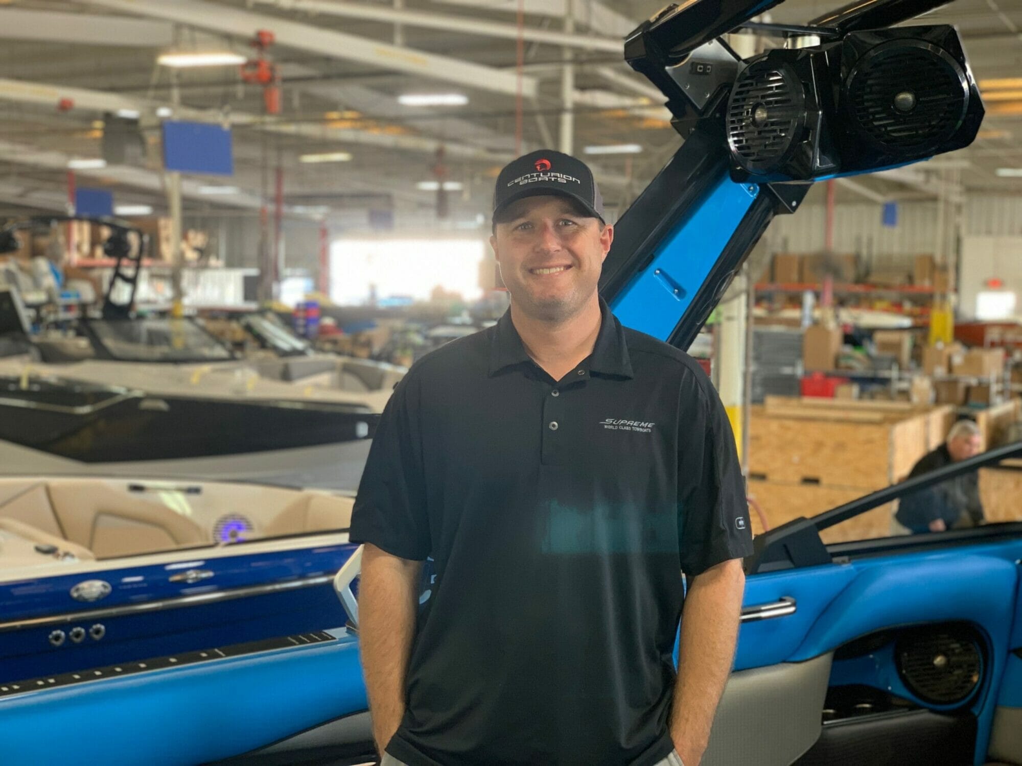 A man standing next to a Supreme boat in a warehouse.