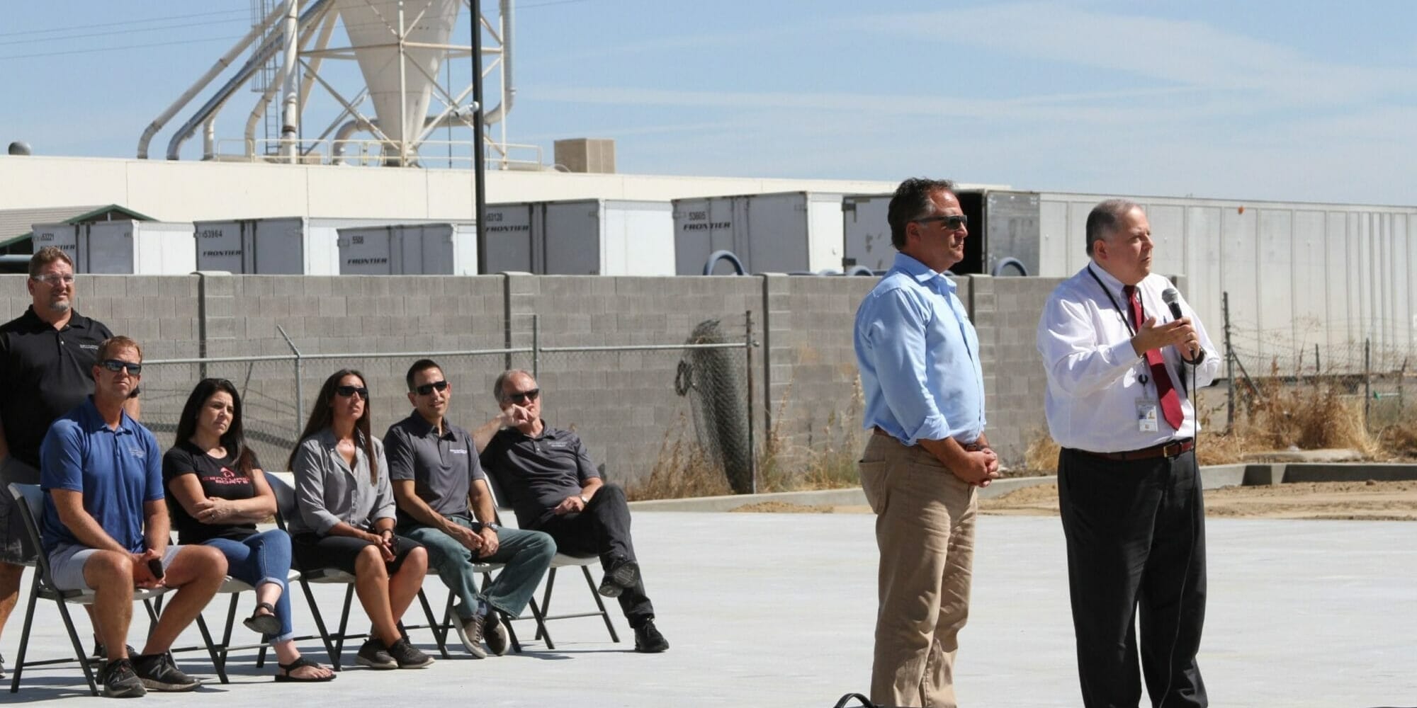 A group of people standing in front of a Supreme building with a microphone.