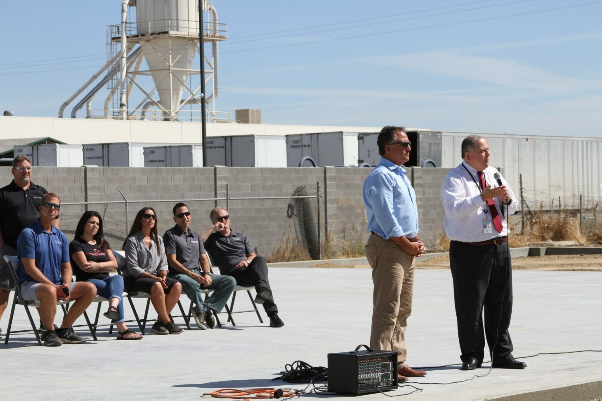 A group of people standing in front of a Supreme building with a microphone.