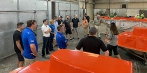 A group of people looking at Supreme boats in a warehouse.