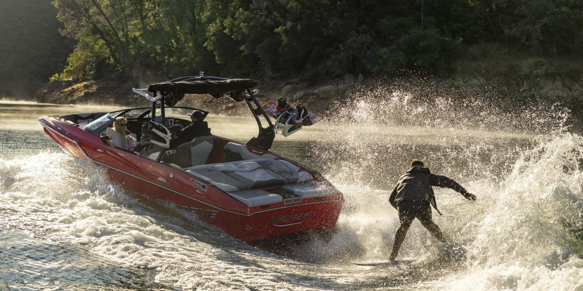 A man is wakeboarding behind a Supreme boat.