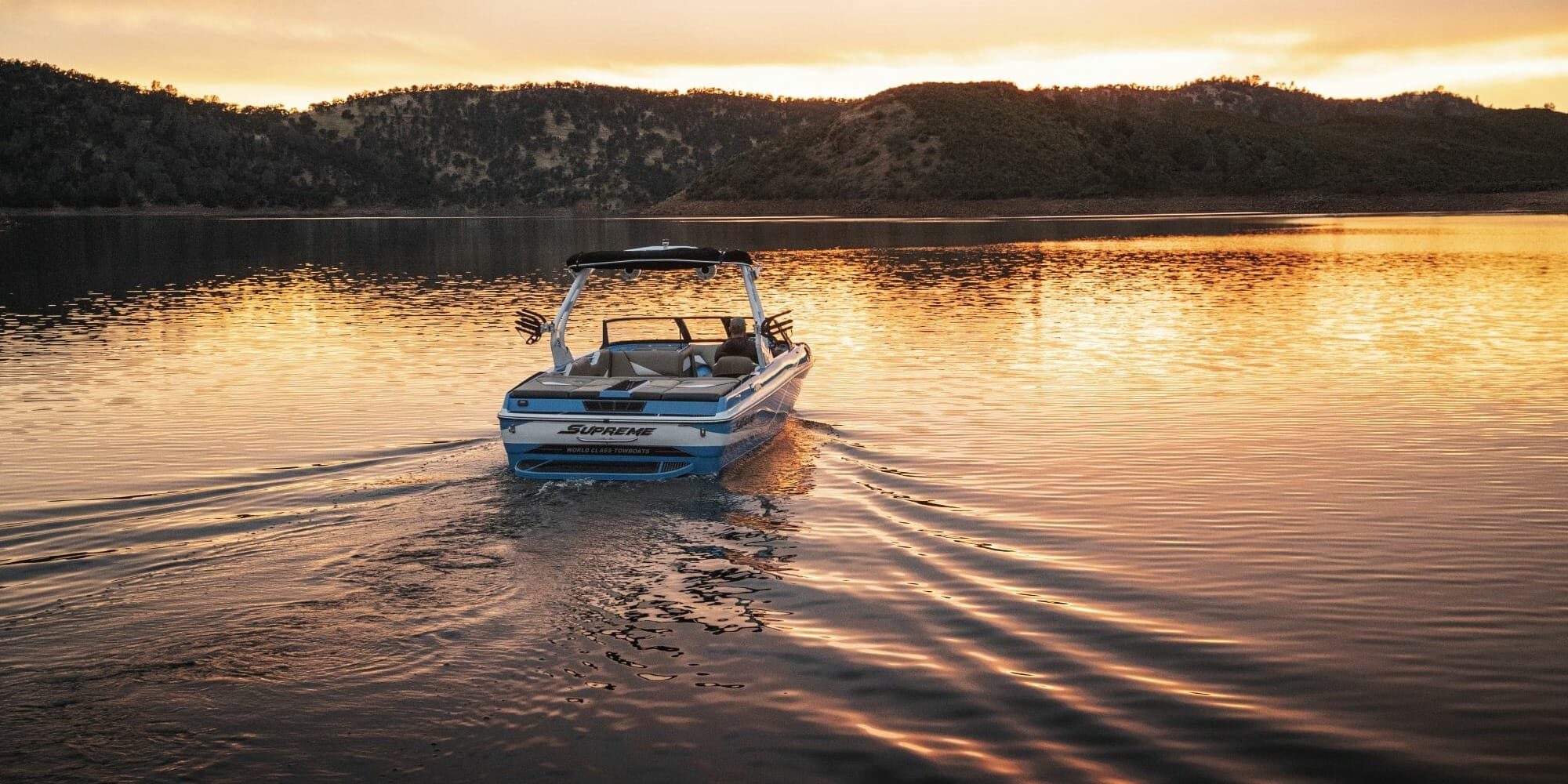 A Supreme boat on a lake at sunset.