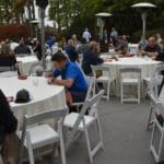 A group of people sitting at tables at an outdoor event featuring Supreme Boats.