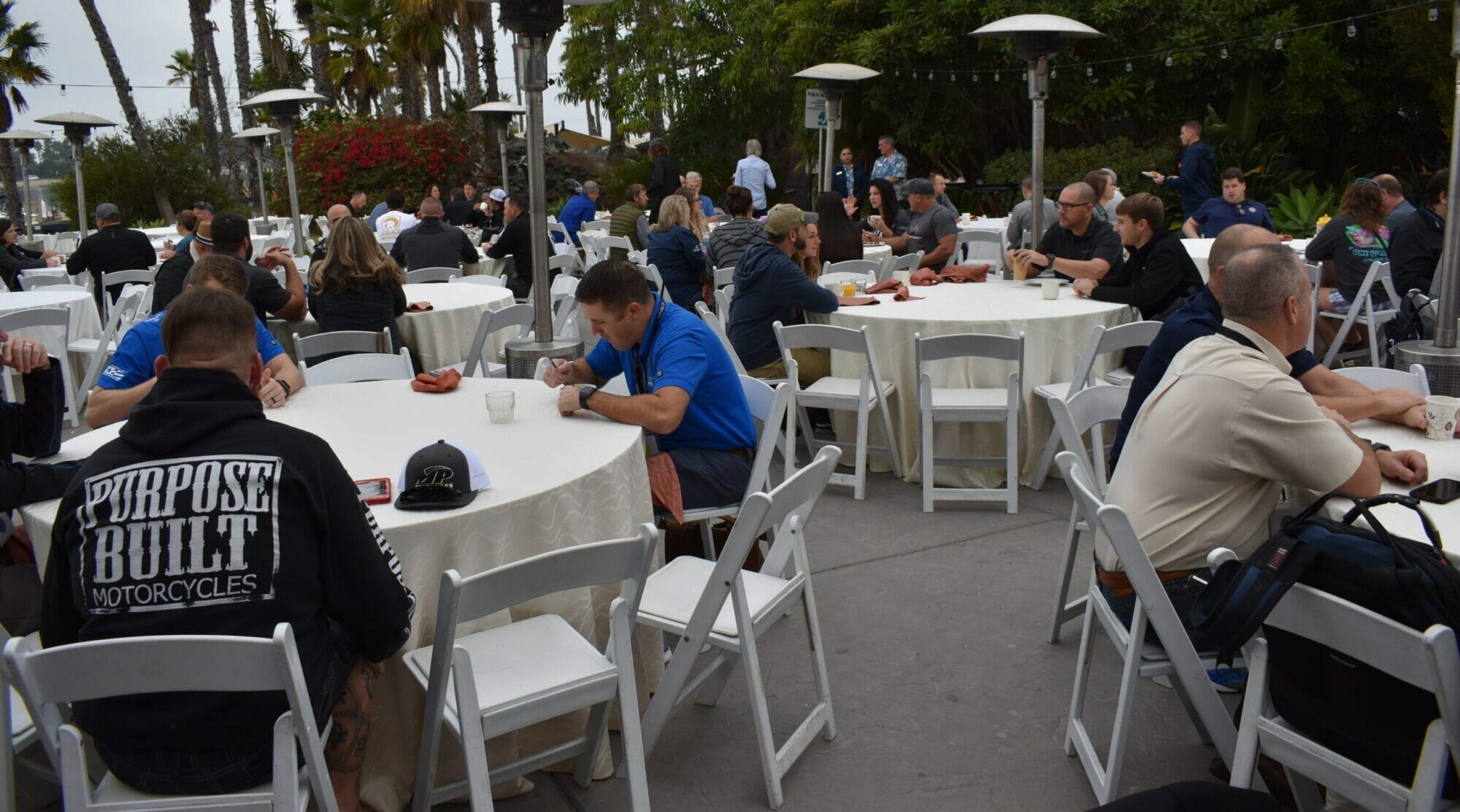 A group of people sitting at tables at an outdoor event featuring Supreme Boats.