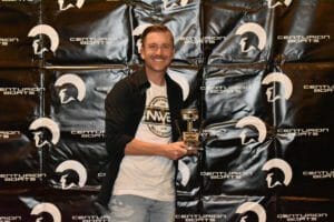 A man holding a Supreme award in front of a wall.