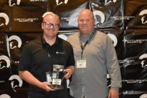 Two men standing next to each other holding a Supreme Boats award.