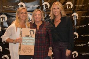 Three women standing in front of a wall with Supreme Boats plaque.