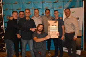 A group of men posing in front of a Supreme banner.