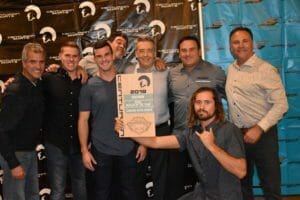 A group of men posing with a Supreme Boats plaque.