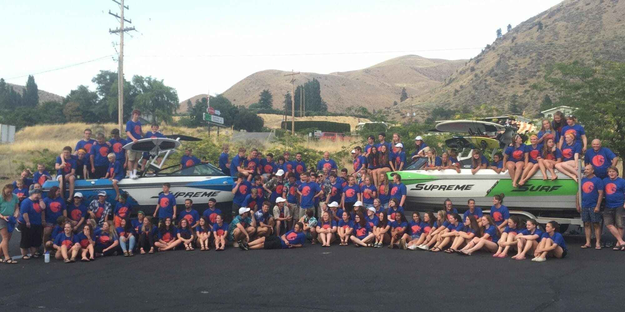 A group of people posing in front of a Supreme boat.