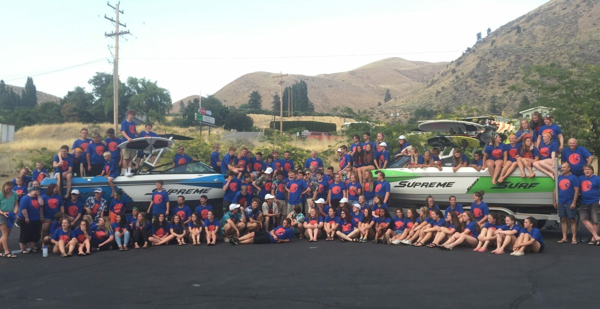 A group of people posing in front of a Supreme boat.