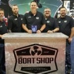 A group of men posing in front of a Supreme boat shop.