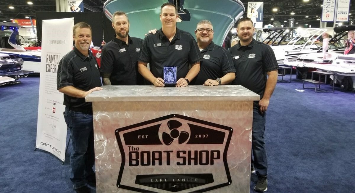 A group of men posing in front of a Supreme boat shop.