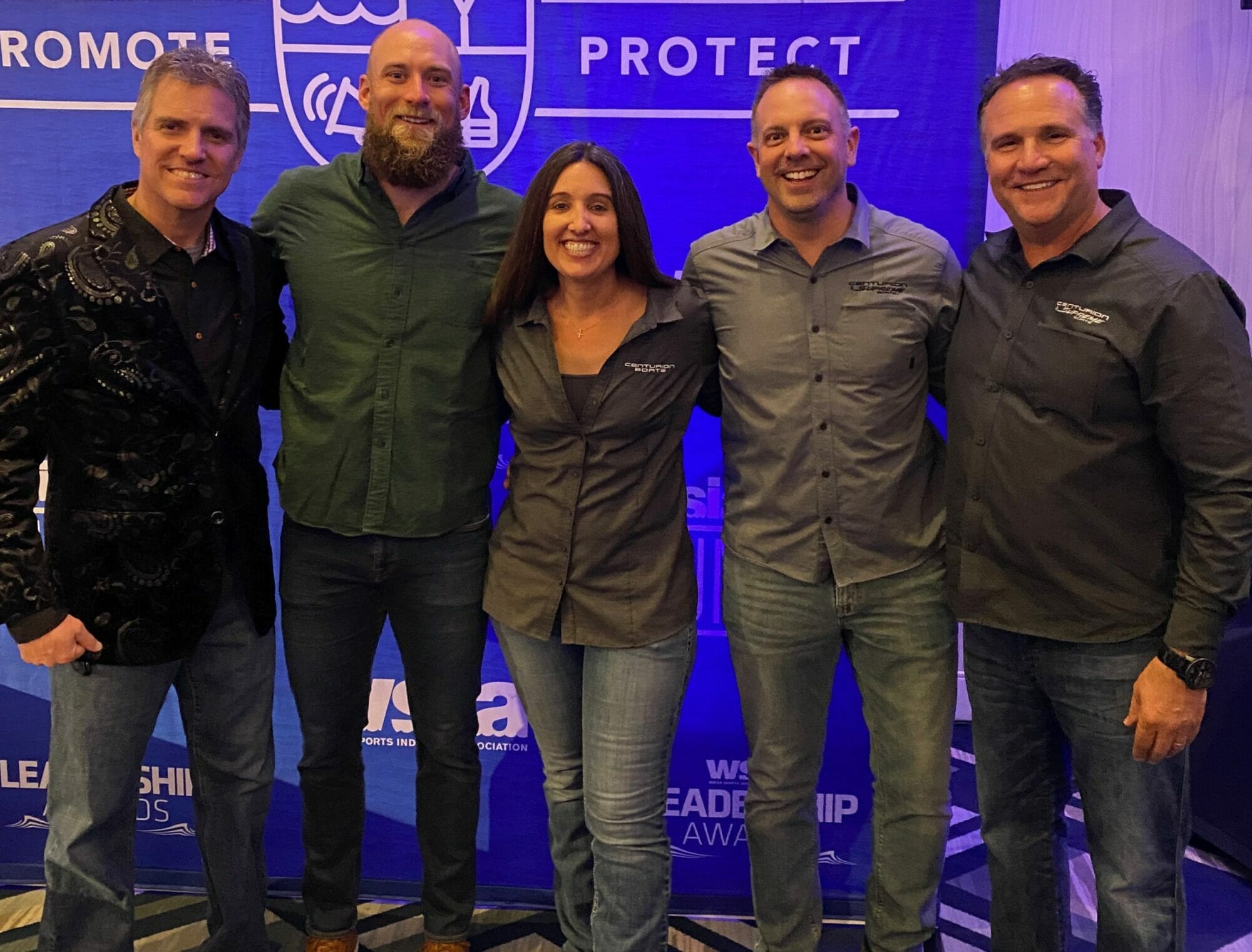 A group of people posing for a picture in front of a Supreme Boats banner.