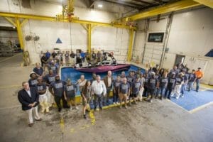 A group of people standing in front of a Supreme boat in a warehouse.