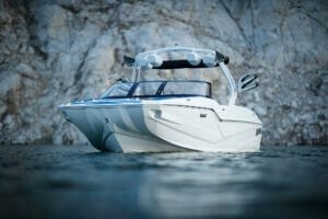 A white Supreme boat is floating near a cliff.