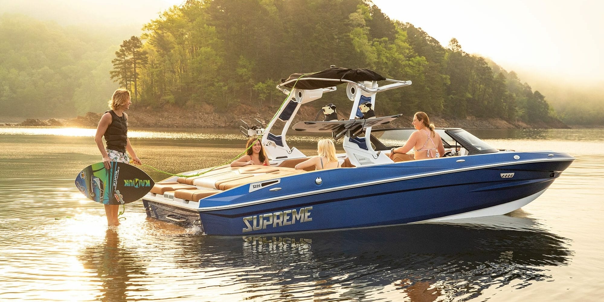 A group of people are standing on a Supreme boat in the water.