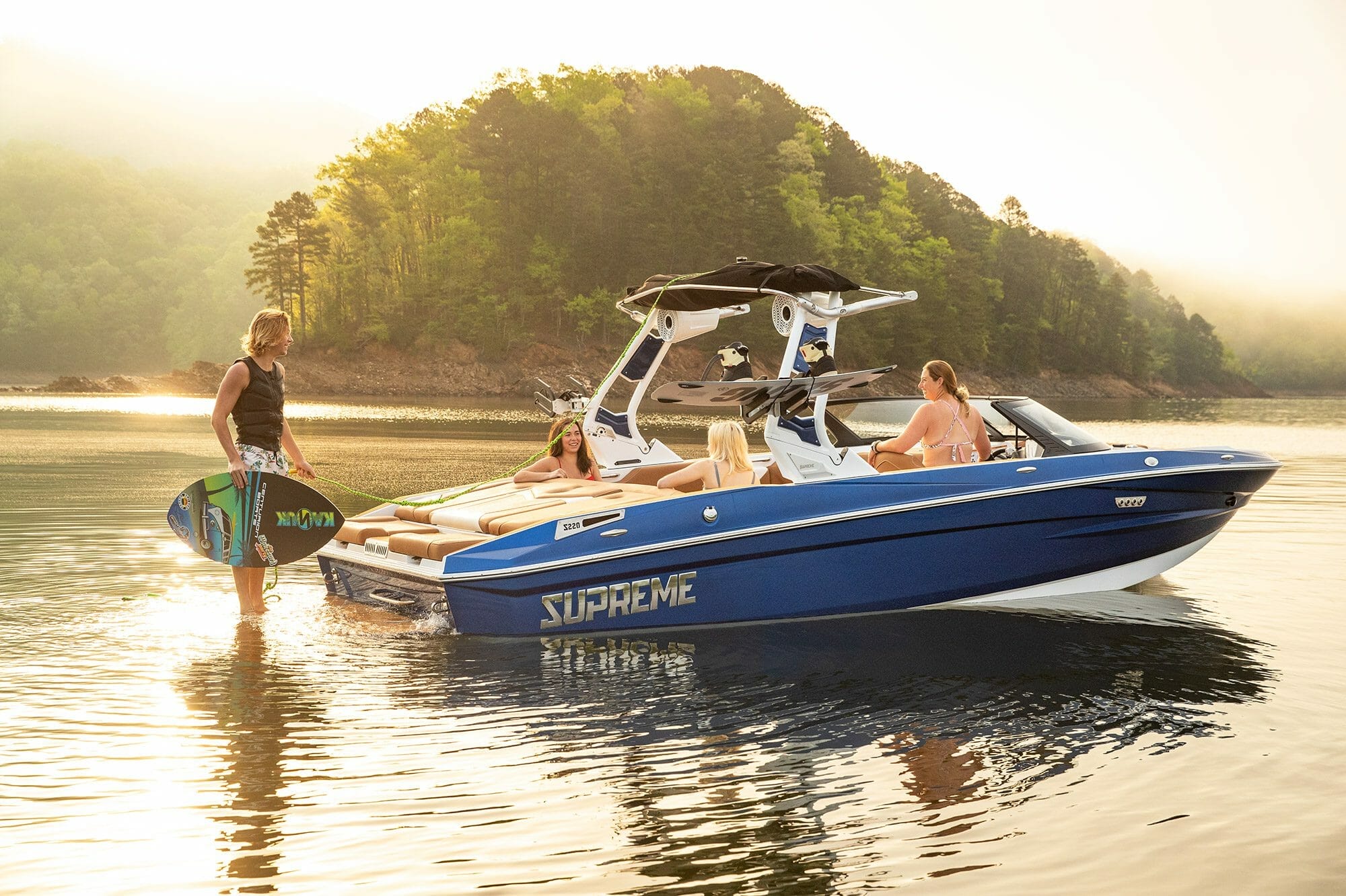 A group of people are standing on a Supreme boat in the water.