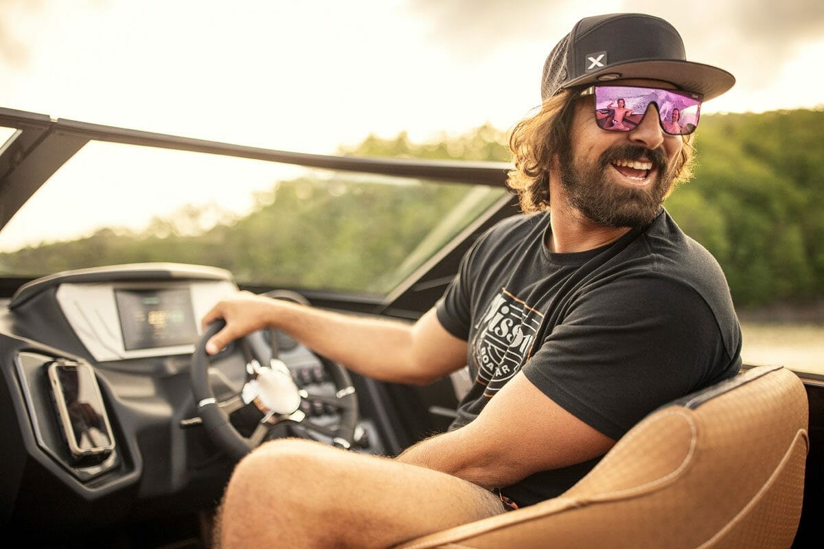 A man wearing sunglasses sitting in the driver's seat of a Supreme boat.