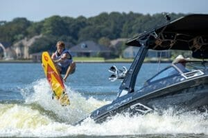 A woman is riding a surfboard on a Supreme boat.