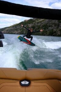 A man is riding a surfboard behind a Supreme boat in the water.