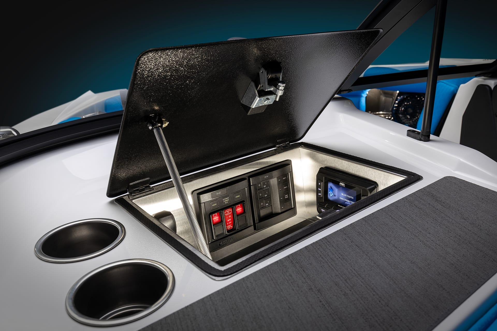 Open compartment on a Supreme Boats S240, revealing electrical controls and switches. Two cup holders are installed beside the compartment.