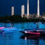 Experiencing the transformative power of water sports as two jet skis navigate the night near a power plant.