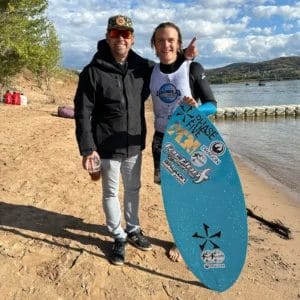 Cade Lybeck posing with a surfboard on a beach.