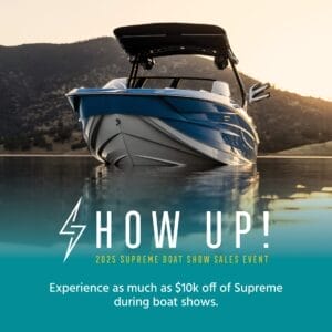 A blue and white Supreme boat sails on tranquil waters, framed by hills in the background. Text: "Show Up! 2025 Supreme Boat Show Sales Event. Experience as much as $10k off Supreme Wakeboats during boat shows.