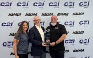 Three people stand proudly in front of a backdrop featuring "CSI" and "NMMA" logos, holding an award together. Their achievement highlights excellence in customer satisfaction, a testament to their commitment at Supreme Boats.