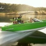 A bright green speedboat from Centurion Boats, with four passengers, moves swiftly across a calm lake with hills in the background.