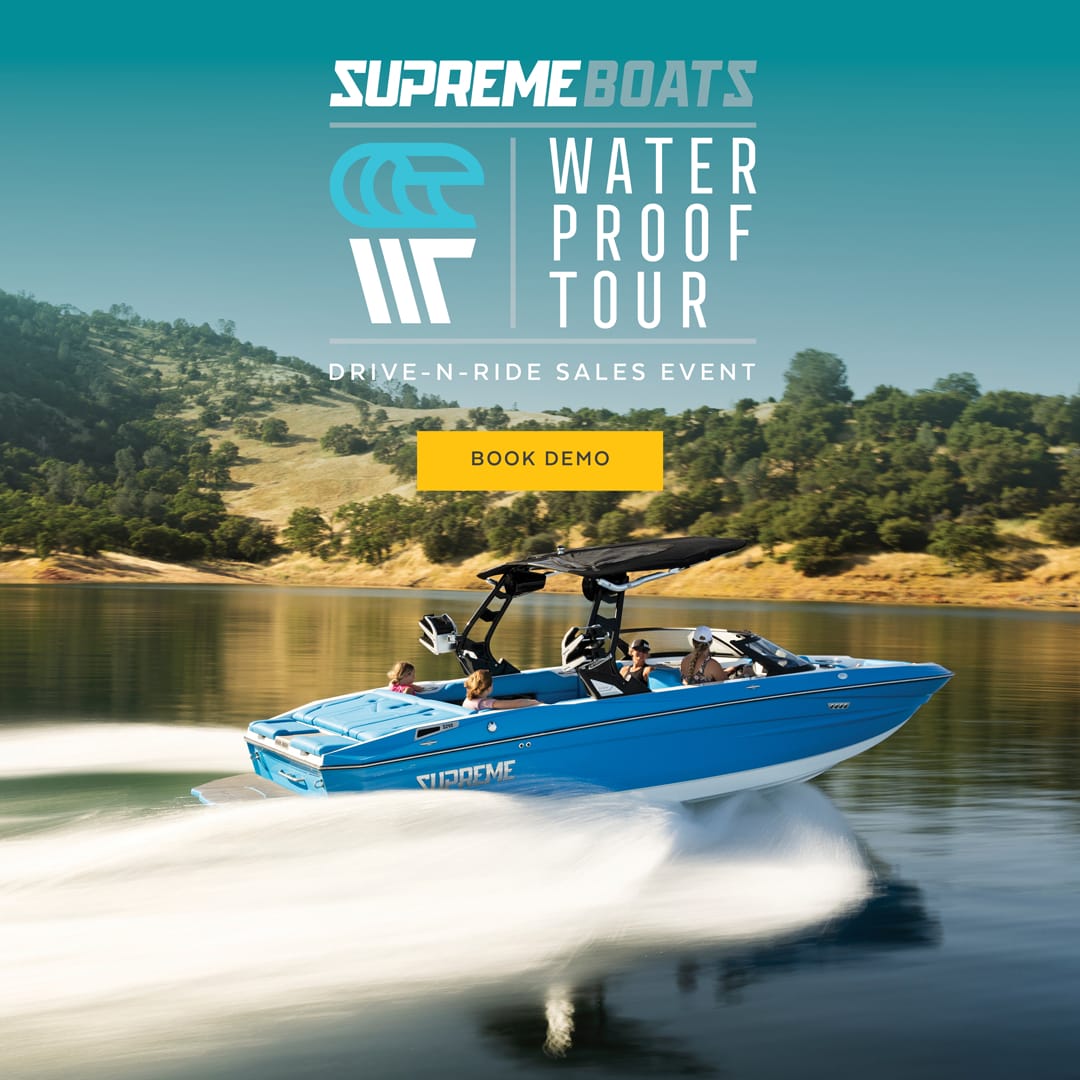 A blue Supreme Wake Boat speeds across the lake with four people aboard. The 