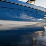 Close-up side view of a blue Supreme boat floating on calm water, its reflection shimmering below—an impressive showcase for any Florida dealership offering Supreme Boats.