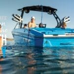 A group of people relax on a blue boat in a lake, with "Supreme Boats 4th of July Independence Day Sale" text displayed on the image.